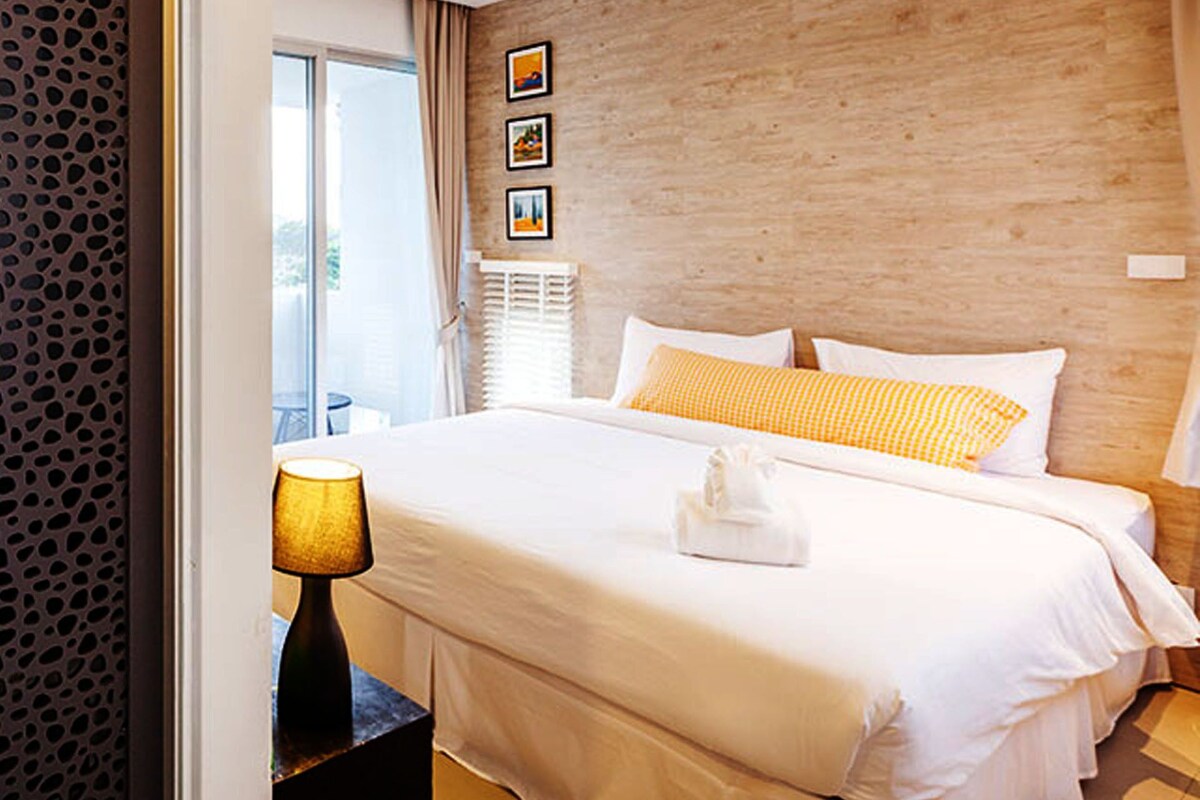 Ein modernes Hotelzimmer mit einem großen Bett, einer Nachttischlampe und einer Wand mit Holzverkleidung.