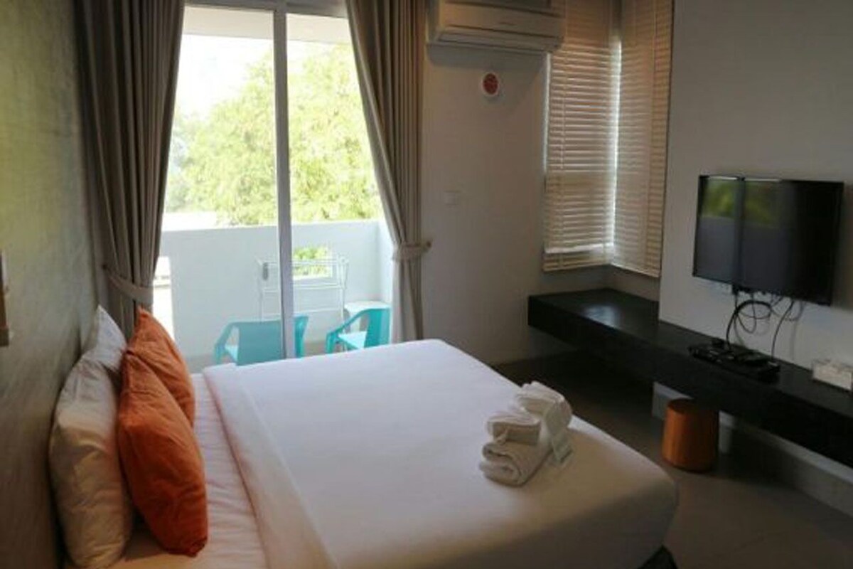 Ein Hotelzimmer mit Bett, Fernseher und einem Balkon mit Stuhl.