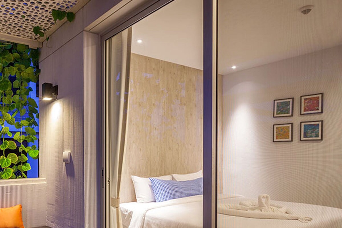 Ein modernes Schlafzimmer mit einem Bett, einer Bank und einer Glastür zum Badezimmer.