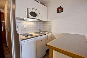 Compact kitchen with microwave, sink, and dishwasher.