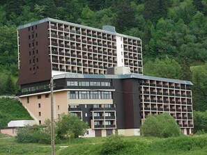 Stunning hotel building with a unique grid-like facade, surrounded by lush greenery.