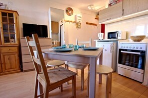 A kitchen with a dining table, chairs, a stove, and a microwave.