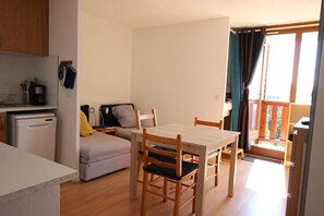 A compact living space with a kitchenette, a dining area, and a balcony.