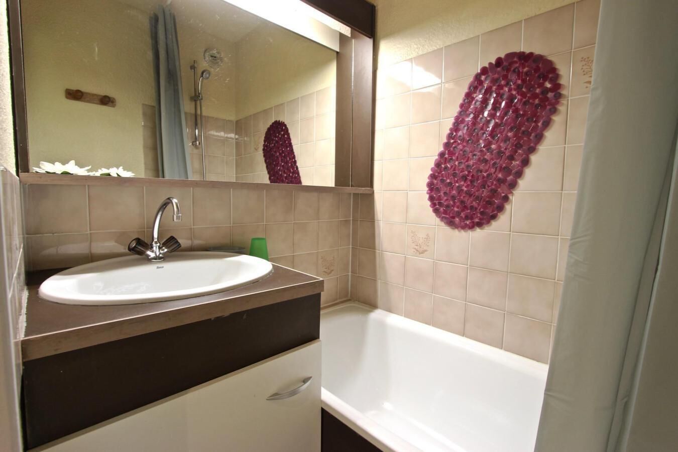 Une salle de bain équipée d’un lavabo, d’un miroir, d’une douche et de carreaux décoratifs.