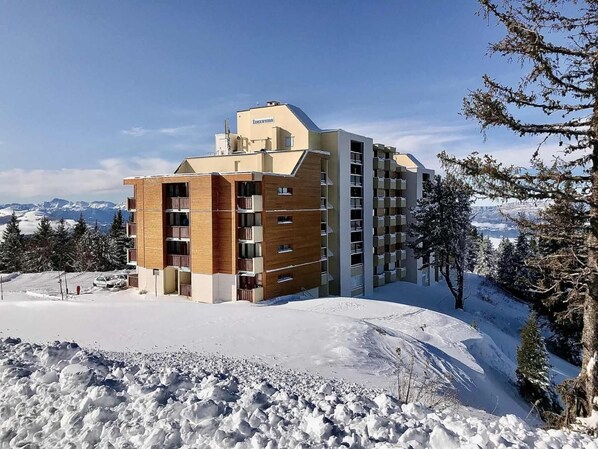 A multi-story hotel with a modern design, located in a snowy mountainous area.