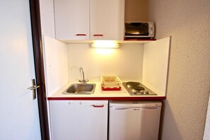 A compact kitchenette with a sink, a microwave, and a stove.