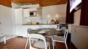 Une cuisine de taille réduite avec des meubles blancs, un four à micro-ondes et une table à manger avec des chaises.