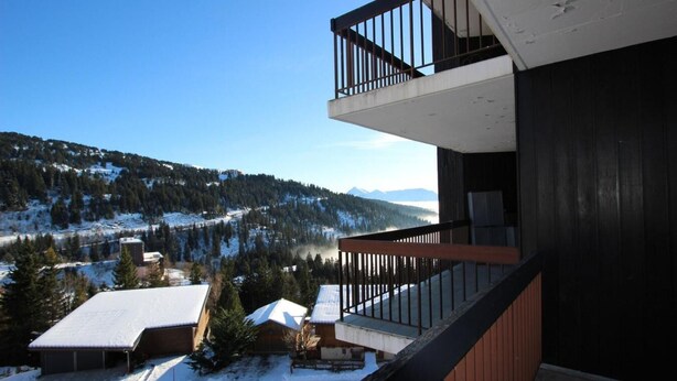 Un bâtiment moderne doté d’un balcon donnant sur un paysage montagneux enneigé.