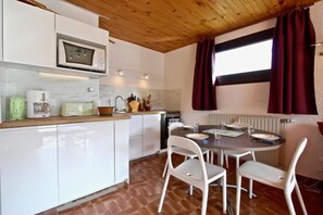 Une cuisine avec des meubles blancs, un four à micro-ondes, une machine à café et une table à manger avec des chaises.