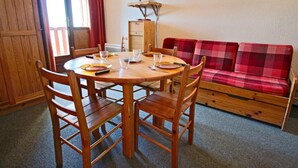 Una mesa de comedor de madera con cuatro sillas, un sofá rojo a cuadros y un aparador de madera.