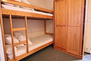 A bunk bed with a wooden wardrobe beside it.