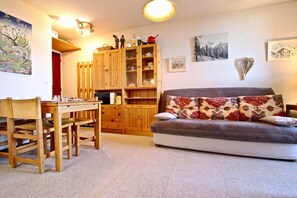 A cozy living room with a sofa, wooden cabinet, and a dining table with chairs. - 100m from ski slopes, 3rd floor, balcony, ski locker, 24m², Chamrousse (Chamrousse)
