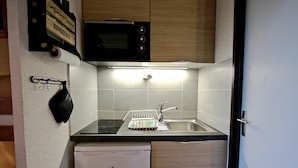 Eine kompakte Küche mit Mikrowelle, Spüle und kleinem Kühlschrank.