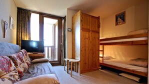 Ein gemütliches Zimmer mit einer Couch, einem Fernseher, einem Etagenbett und einem kleinen Tisch.
