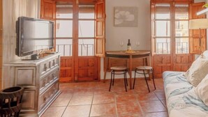 Una habitación acogedora con televisión, muebles de madera, una mesa de comedor con sillas y un sofá.