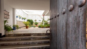 Un patio con escalones que conducen a un edificio blanco, rodeado de plantas en macetas.