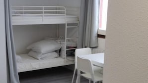 A room with a bunk bed, a desk, and a chair.