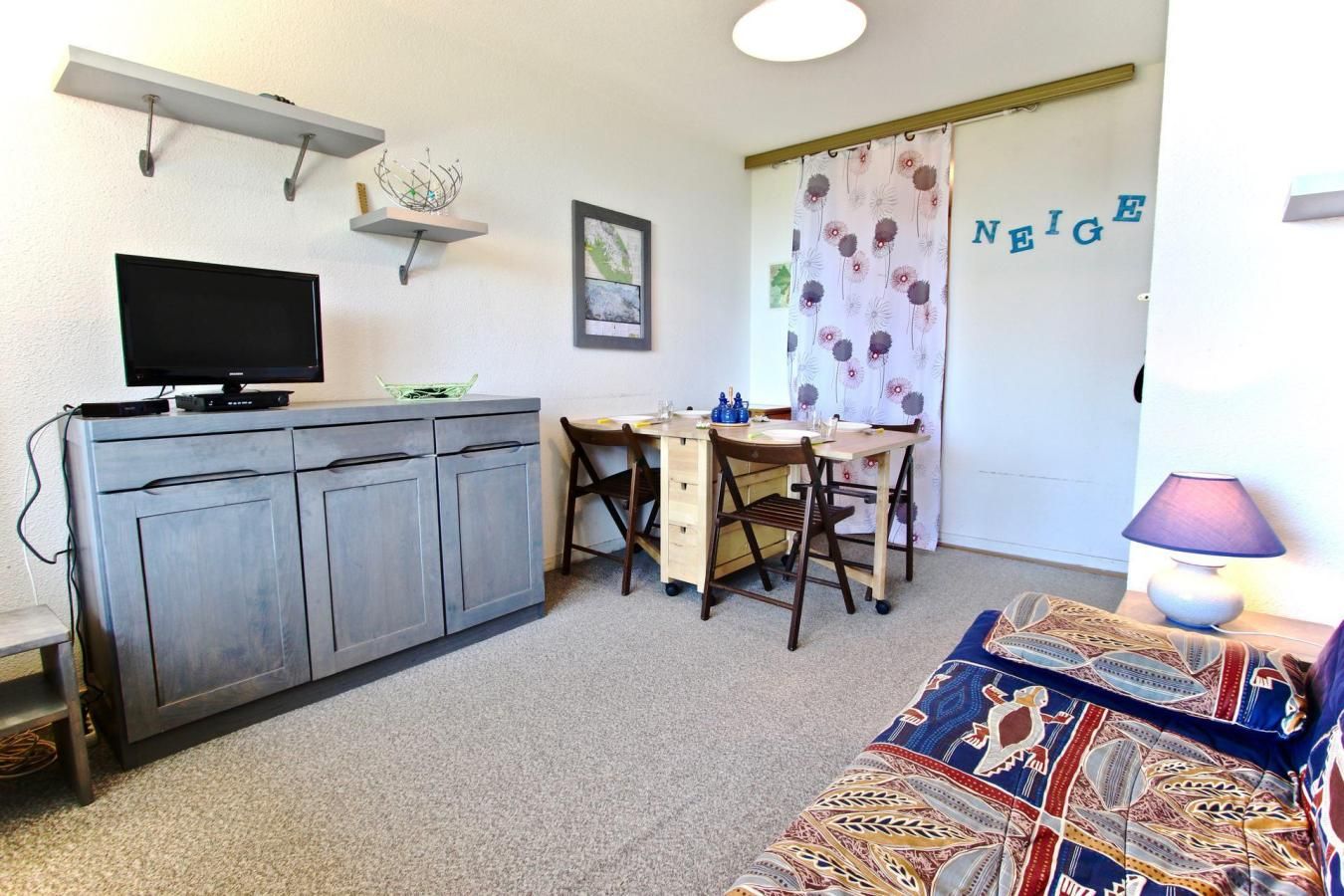Un espacio habitable compacto con kitchenette, zona de comedor y sofá.