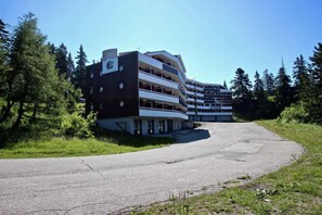 A multi-story building with a modern architectural design, featuring balconies and a parking area in front. - 100m from ski slopes, 3rd floor, tv, ski locker, 21m², Chamrousse (Chamrousse)