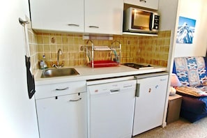 A compact kitchen with a microwave, sink, and dishwasher.
