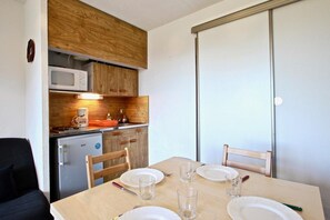 Una cocina compacta con microondas, un refrigerador pequeño y armarios de madera.