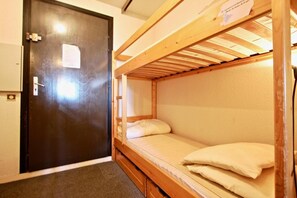 A single bunk bed room with a door and a small window.