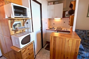 A compact kitchen with a microwave, stove, and wooden cabinets.