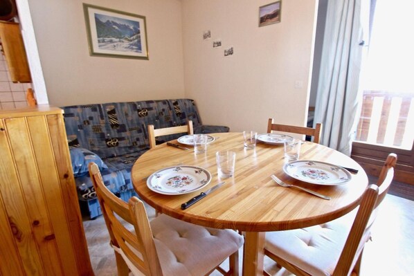 A dining area with a round wooden table set for four, surrounded by wooden chairs.