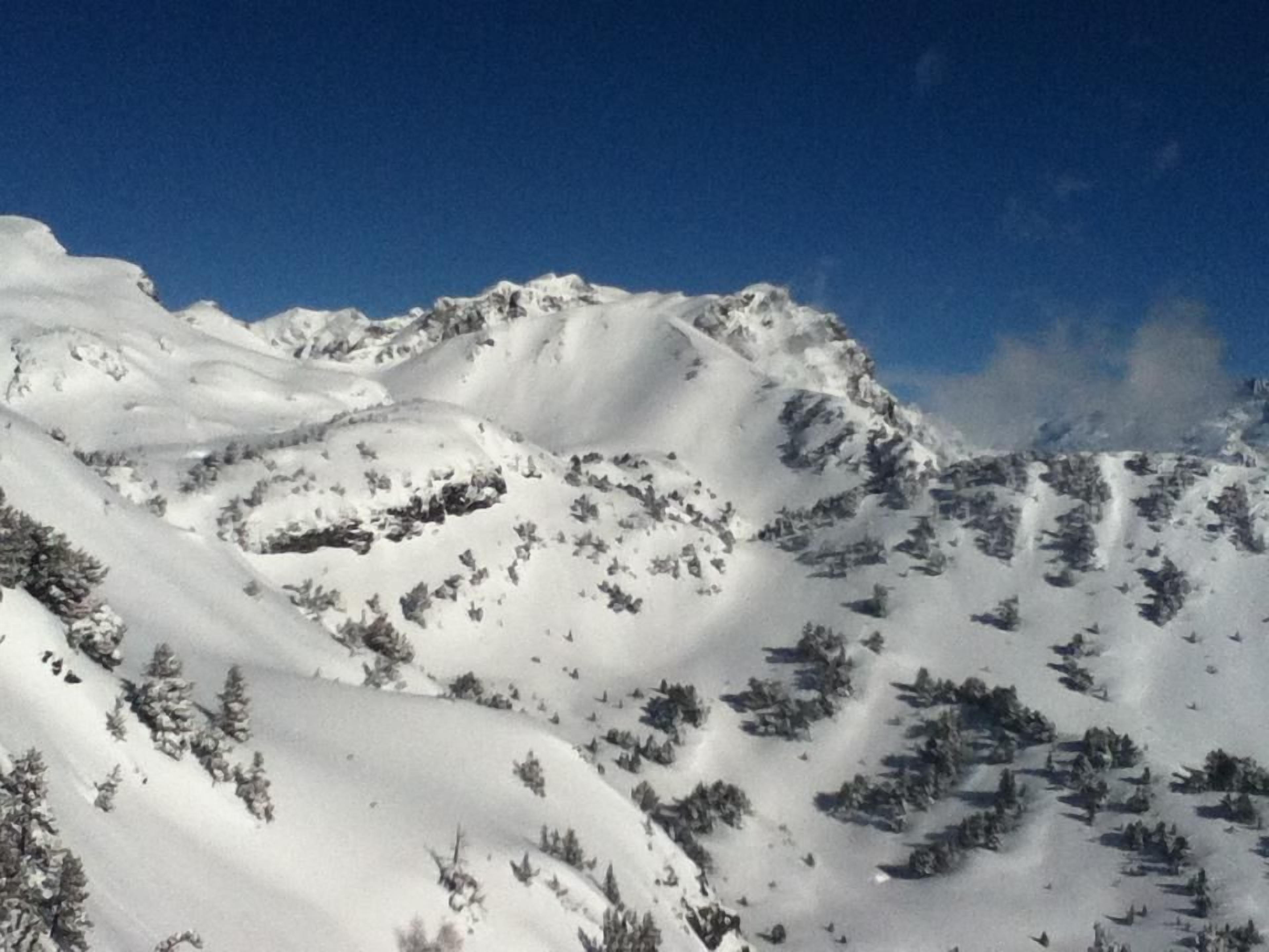 A snow-covered mountain landscape with rugged terrain and sparse vegetation.