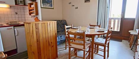 Cocina compacta con zona de comedor, un sofá y vistas por un ventanal.