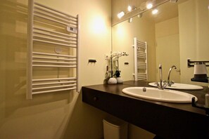 Une salle de bain moderne avec deux lavabos, un miroir et des porte-serviettes.