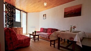 A cozy living room with a sofa, a table set for dining, and a painting on the wall. - 300m from ski slopes, 6th floor, balcony, tv, 27m², Chamrousse (Chamrousse)