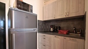 A kitchen with a stainless steel refrigerator, wooden cabinets, a coffee maker, and a red basket. - 300m from ski slopes, 6th floor, balcony, tv, 27m², Chamrousse (Chamrousse)