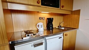 Pieni, käytännöllinen keittiönurkkaus, jossa on mikroaaltouuni, kahvinkeitin ja pieni jääkaappi.