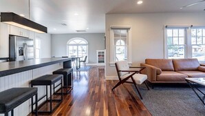 Een moderne keuken met een bar, houten vloeren en een zithoek met een bank en stoelen.