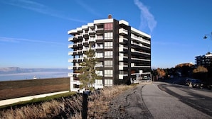 Un immeuble à plusieurs étages doté de balcons, un ciel dégagé et une vue sur le paysage.