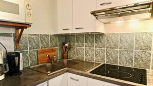 Une cuisine avec des meubles blancs, un évier, une cuisinière et un four à micro-ondes.