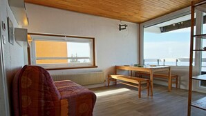 Une pièce chaleureuse avec un plafond en bois, une grande fenêtre offrant une belle vue, un banc en bois et une table.