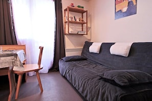 Ein Zimmer mit einem Holzhocker, einer Couch, einem kleinen Tisch und einem Bücherregal.