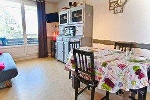 Ruokailutila, jossa on neljälle katettu ruokapöytä, pieni keittiönurkkaus, jossa on mikroaaltouuni, ja ikkunasta avautuva näkymä ulos.
