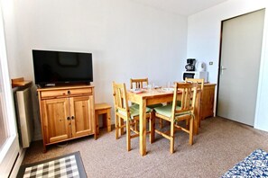 A compact living space with a wooden dining table, four chairs, a television on a cabinet, a coffee maker, and a microwave. - 2nd floor, balcony, tv, ski locker, 21m², Chamrousse (Chamrousse)