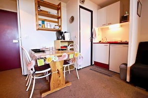 A compact living space with a dining table, chairs, a kitchenette, and a small seating area.