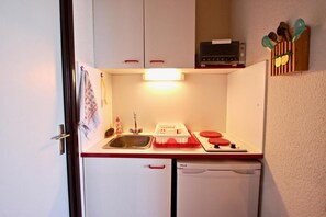 A compact kitchenette with a sink, a small stove, and a microwave.