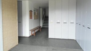 Un couloir avec un banc, un escalier et des casiers.