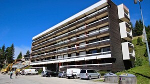 Un immeuble à plusieurs étages doté de balcons, d’un espace de stationnement et situé dans une rue piétonne.