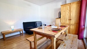 Un coin repas avec une table en bois dressée pour deux personnes, un banc, un canapé et un buffet en bois.