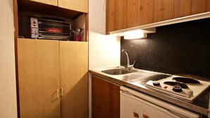 Une cuisine de taille réduite, dotée de meubles en bois, d’un évier, d’une cuisinière et d’un réfrigérateur.