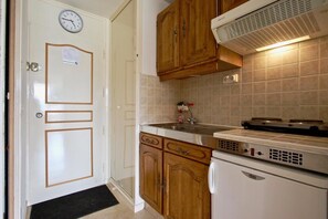 A kitchen with wooden cabinets, a built-in stove, and a refrigerator. - Ground floor, balcony, tv, 19m², Chamrousse (Chamrousse)