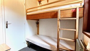 A bunk bed with a ladder, a door, and a radiator. - 300m from resort center, 2nd floor, balcony, tv, 55m², Chamrousse (Chamrousse)