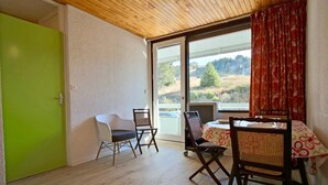 Une pièce avec un plafond en bois, une porte verte et une table entourée de chaises.